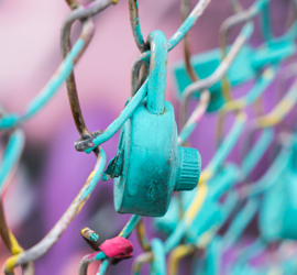 turquoise lock on a chain mail fence with a purple background signifying unlocking sexual violence
